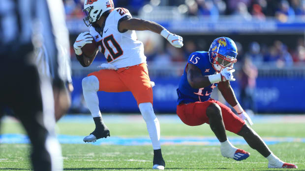 Oklahoma State running back Dominic Richardson (20) spins around Kansas redshirt junior linebacker Craig Young (15) in the first quarter of Saturday's game inside David Booth Kansas Memorial Stadium.